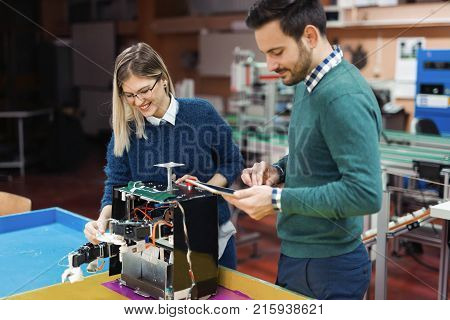 Young attractive students of mechatronics working on project together