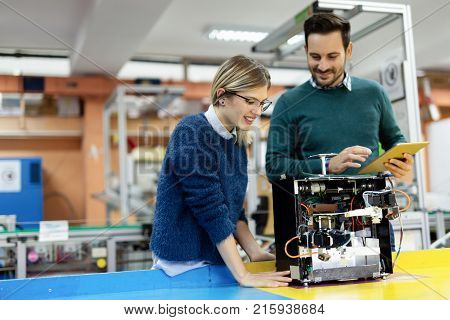 Young attractive students of mechatronics working on project together