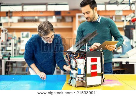 Young attractive students of mechatronics working on project together