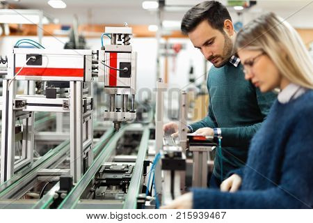 Young attractive students of mechatronics working on project together