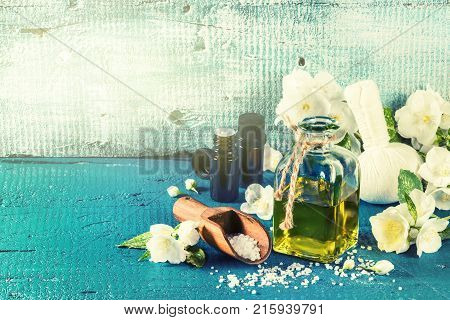 Spa setting with jasmine flowers and essential oil over old blue wood background. Wellness concept