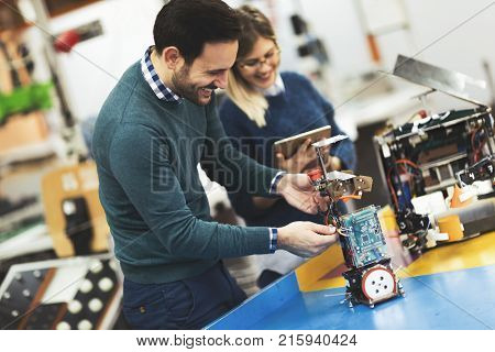 Young attractive students of mechatronics working on project together