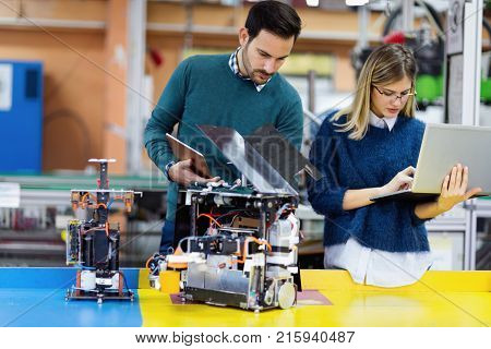 Young attractive students of mechatronics working on project together