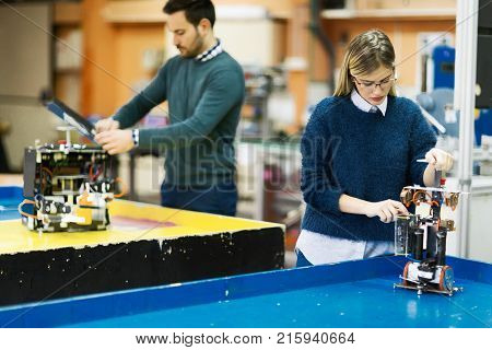 Young attractive students of mechatronics working on project together