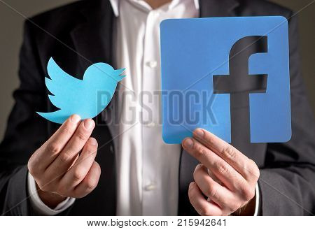 JYVASKYLA FINLAND - JULY 23 2017: Man in a suit holding printed carboard Twitter and Facebook logo. Both companys are known for their social media services and websites. Illustrative editorial.