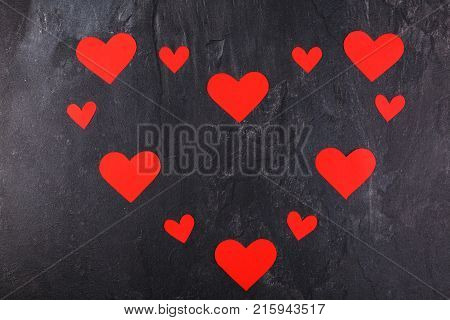 The hearts are red, carved in different sizes, lined up in one big heart on a stone background