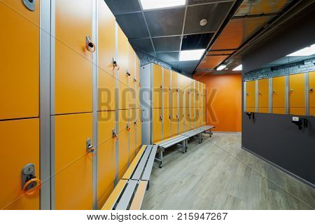 Room with orange lockers at fitness center.