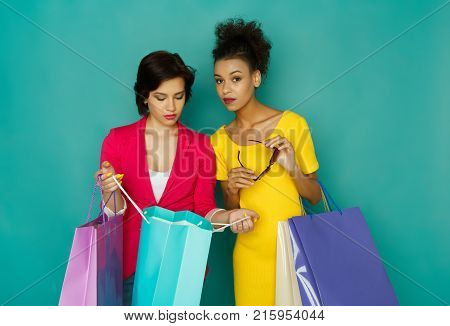 Happy Multiethnic Girlfriends With Shopping Bags. Two Excited Shopaholics Boasting With Purchases At