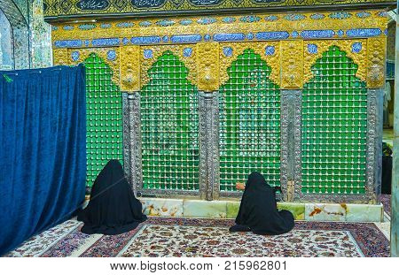 YAZD IRAN - OCTOBER 17 2017: Women sit on carpet and pray in front of tomb in Shahzade Fazel Holy Shrine on October 17 in Yazd