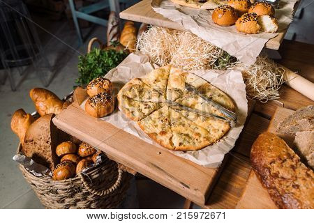 Assortment of different kind of cereal bakery: bread, pasties, buns, pretzel and croissant on old wooden background.