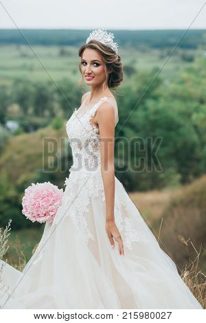 Portrait Of A Young Beautiful Bride On A Background Of A Gorgeous View Of The River And Fields.