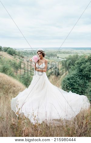 Portrait Of A Young Beautiful Bride On A Background Of A Gorgeous View Of The River And Fields.