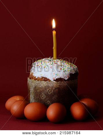 Trendy photo of Easter cake with the candle on a top. Orthodox holidays traditional stuff on a dark purple background. Minimal concepth photo.