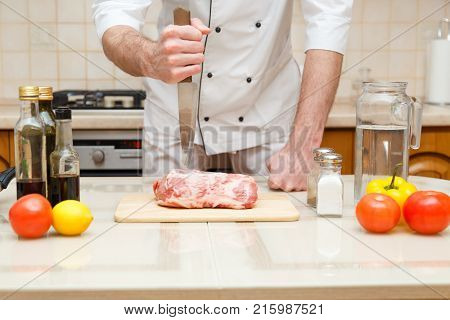 Butcher cutting meat on chopping board, professional cook holding knife and cutting meat