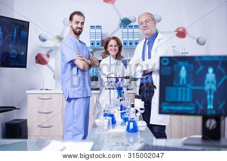 Smiling Scientist Colleagues In Their Uniform Standing In Chimical Lab