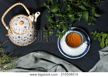 teapot and cup of herbal tea with nerbs