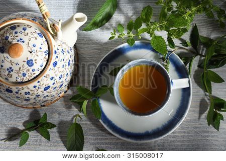 teapot and cup of herbal tea with nerbs