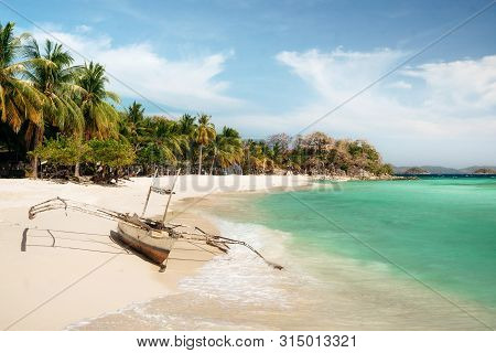 Tropical Malcapuya Island With Traditional Philippines Bangka Boat, Azure Water And White Sand Beach