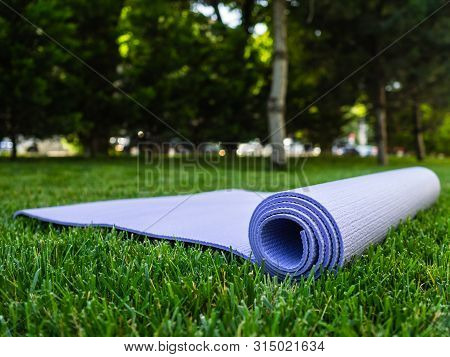 Yoga Or Fitness Mat. Mat For Sports On The Green Grass In The Park. Exercise In The Fresh Airyoga Or