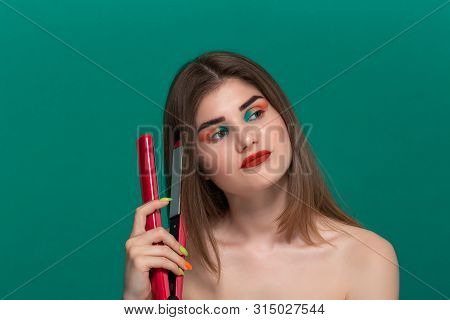 Portrait Of Sceptic Beautiful Young Woman With Bright Color Make-up Doing Hair Style Herself With A 