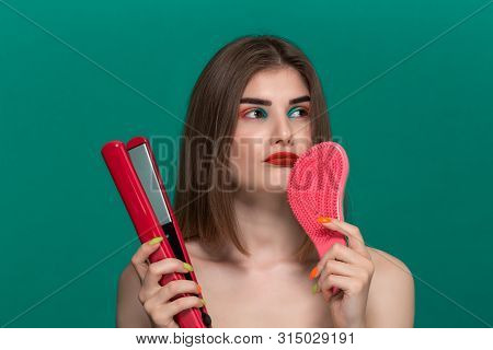 Portrait Of A Thoughtful Beautiful Young Woman With Bright Color Make-up Doing Hair Style Herself Wi