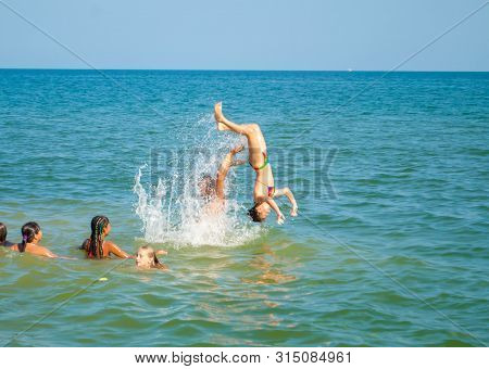 Odesa Rgn. Ukraine, July 29, 2018: Teenager Throws Up A Girl In The Sea, And She Jumps Into The Wate
