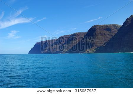 Na Pali Coastline, On The Island Of Kauai, Hawaii, Is Rugged And Steep.  Steep Cliffs Meet Vivid Blu
