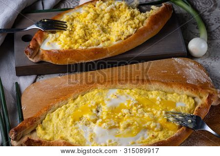 Two people eat Adzhar khachapuri. Stuffing from cheese, eggs and butter. Oven cake served for food. 