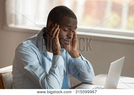 African Guy Sitting Near Computer Rubbing Temples Feels Unwell