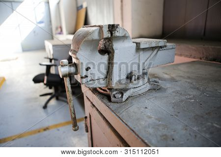 Shallow Depth Of Field Image With A Rusty And Dirty Heavy Iron Vice On A Workbench Inside A Workshop