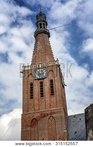 Ancient Church Tower In The Small Dutch Town Of Medemblik On A Background Of Blue Cloudy Sky. Vertic