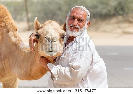 Al Ain, Uae - March 27, 2019: Man Selling Hay Stacks On The Side Of The Road Near Al Ain, Uae Posing