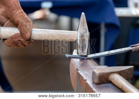 Unrecognizable Blacksmith Forging Red-hot Metal With Hammer. Blacksmithing Concept.
