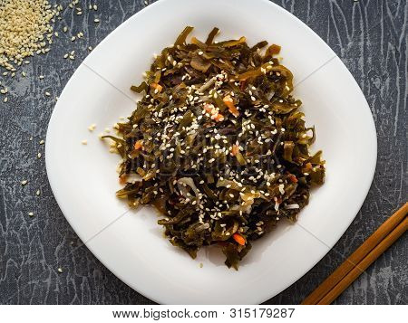 Seaweed Salad With Sesame Seeds Is On A White Plate