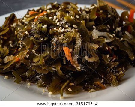 Seaweed Salad With Sesame Seeds Is On A White Plate