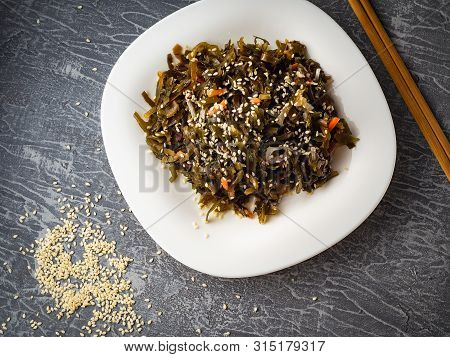 Seaweed Salad With Sesame Seeds Is On A White Plate