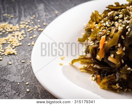 Seaweed Salad With Sesame Seeds Is On A White Plate