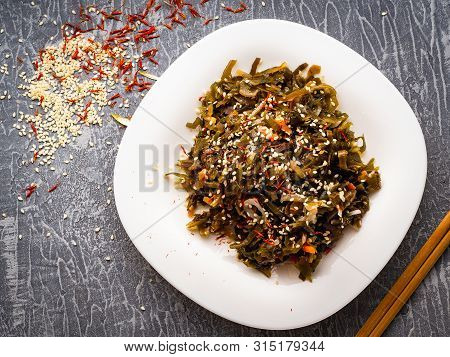 Seaweed Salad With Sesame Seeds Is On A White Plate