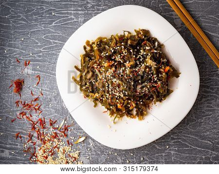 Seaweed Salad With Sesame Seeds Is On A White Plate