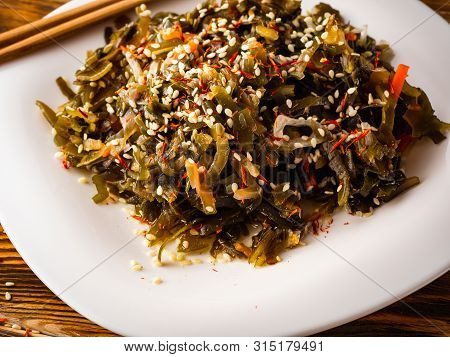 Seaweed Salad With Sesame Seeds Is On A White Plate