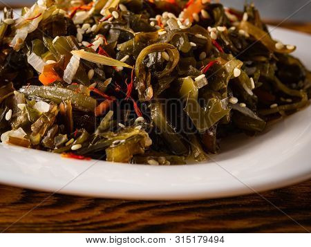 Seaweed Salad With Sesame Seeds Is On A White Plate