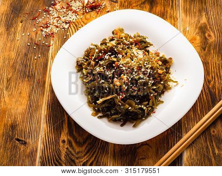 Seaweed Salad With Sesame Seeds Is On A White Plate