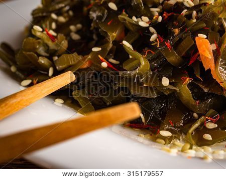 Seaweed Salad With Sesame Seeds Is On A White Plate