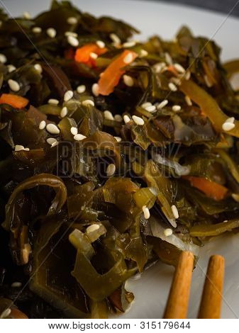 Seaweed Salad With Sesame Seeds Is On A White Plate
