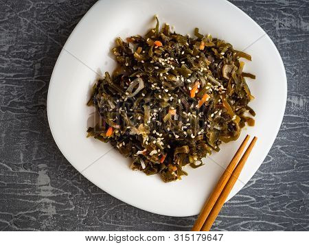 Seaweed Salad With Sesame Seeds Is On A White Plate