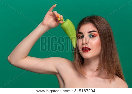 Closeup Portrait Of Beautiful Young Woman With Bright Color Make-up Holding Green Pepper Standing Is