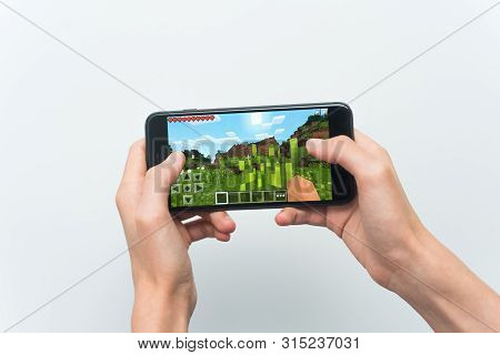 Samara, Russia -07, 29, 2019: A Young Guy Playing Minecraft Game On Iphone 8 Plus. Teenage Boy Holdi