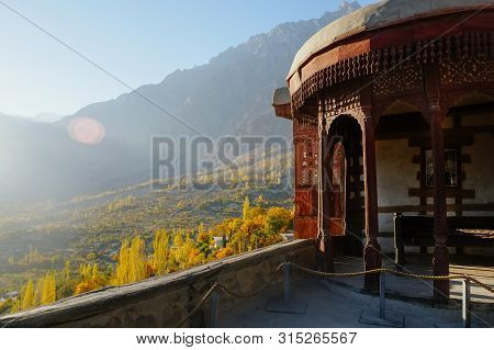 Morning Sunlight Lit Colorful Forest Trees In Hunza Valley Against Karakoram Mountain Range In The B