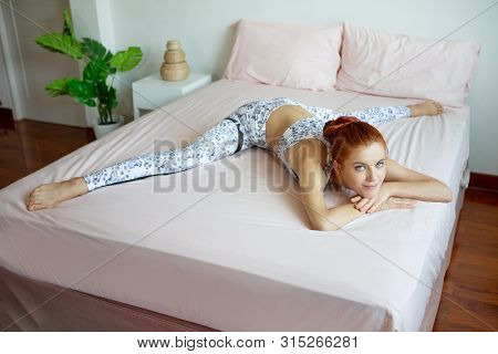 Young Fitness Woman In Sportwear Practicing Yoga On Bed In Bedroom At Home In Morning . Sport Girl L