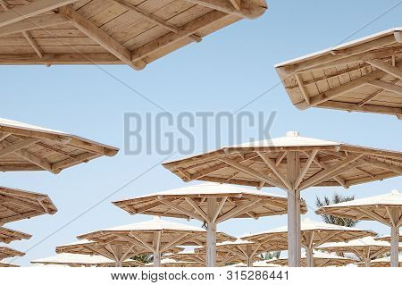 Hats Of Wooden Beach Umbrellas Against The Blue Sunny Sky In Summer